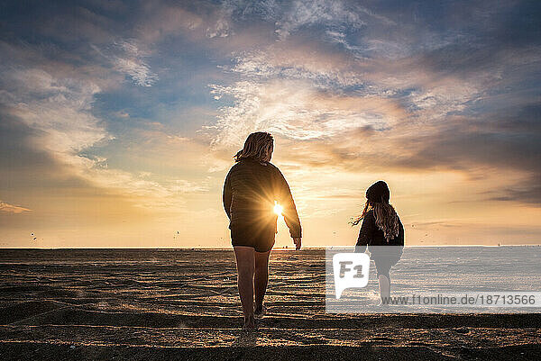 Sisters walking down the beach at sunset