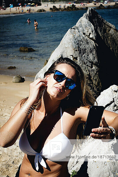 Blond woman with sunglasses using wireless headset and mobile phone.