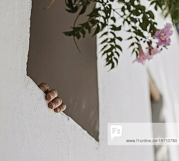 A hand holds on to a window sill of a stucco building in Marrakesh