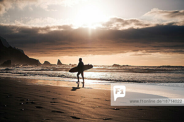 Surfer walking at the beach at sunset in Tenerife