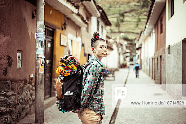Portrait of funky female traveler with back pack and colourful fabric