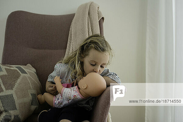 young girl kissing her dolls head