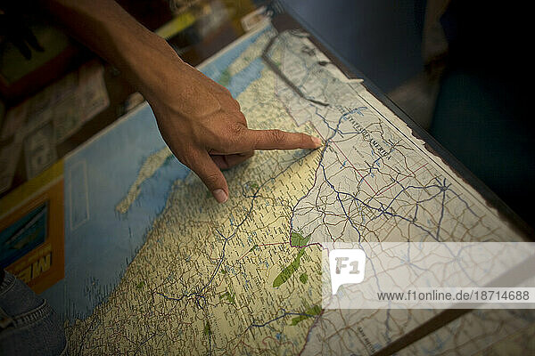 An undocumented migrant  traveling across Mexico to work in the United States  points to the border area on a US map in a shelter for migrants located along the railroad in Mexico