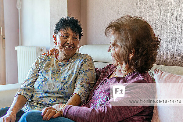 two elderly friends talking sitting on the sofa