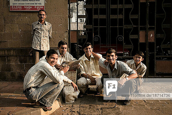 A group of young men hang out on a sidewalk during sunset.