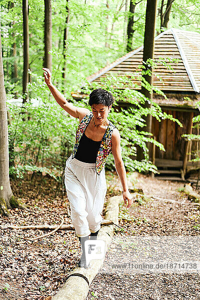 asian dancer balances on wooden railing from treehouse in forrect