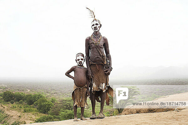 A grandmother stands with her grandson dressed in traditional clothing overlooking the Omo Valley in southern Ethiopia.