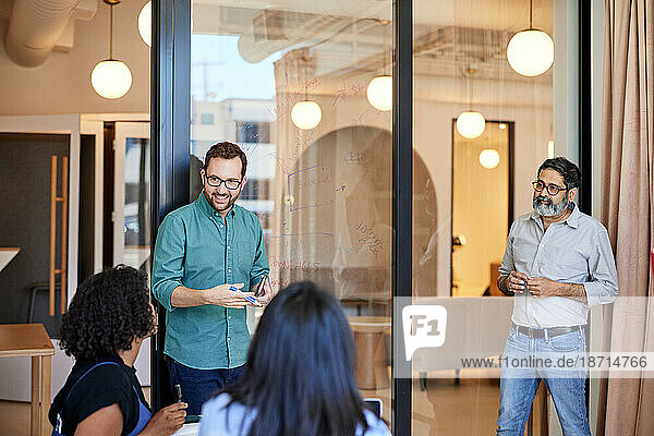 Smiling male entrepreneur conducting business meeting with coworkers