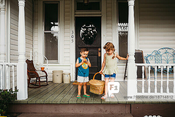 Young boy and girl on front porch with basket of fresh peaches