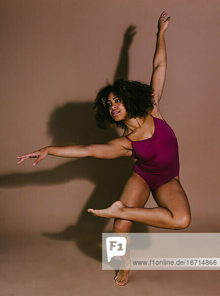 Female dancer in pink leotard with shadow on wall in studio