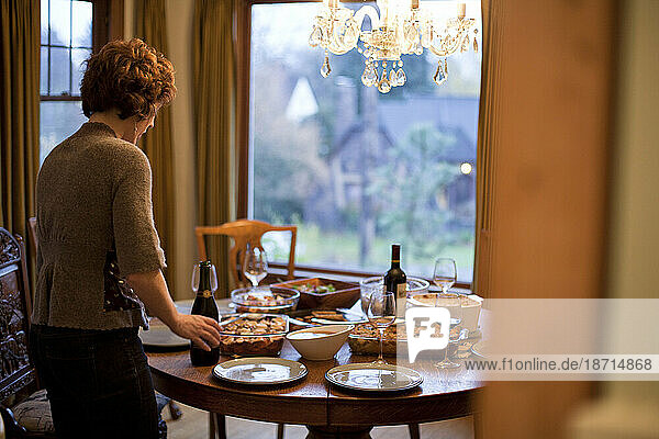 A woman sets a plate down on a Thanksgiving tabletop full of homemade dishes in Portland  Oregon.
