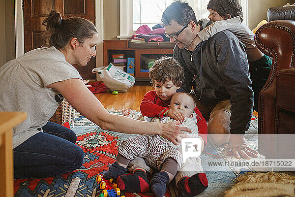 A family wrestles together on the living room floor