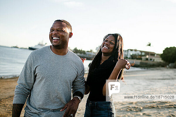 Father and daughter laughing together on beach at sunset