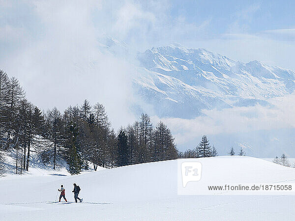 Two winter hikers are walking at the mountain plateau of Moosalp in the Swiss Walliser Alps.