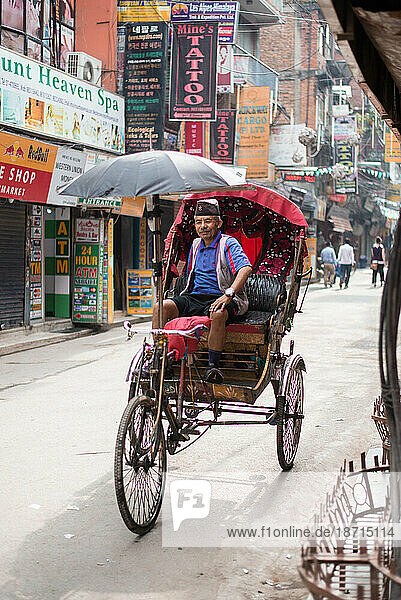Smiling man driving bicycle cart through streets of Nepal