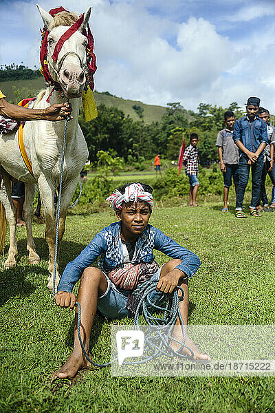 Boy sitting with horse at Pasola Festival  Sumba island  Indonesia