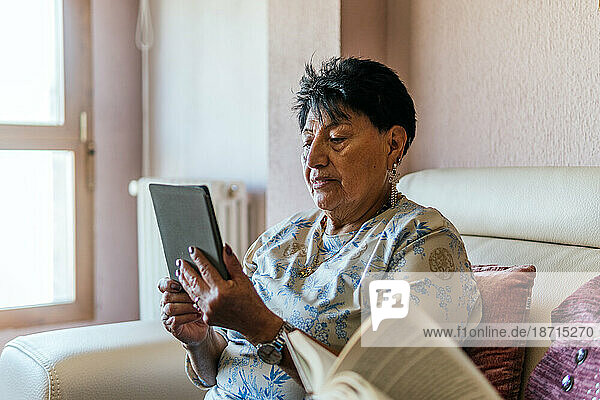 latin american woman reading with an electronic book