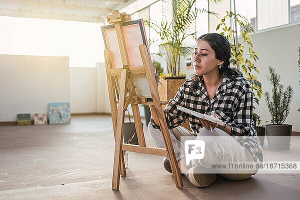 Artist woman painting on canvas at sunset. Natural light