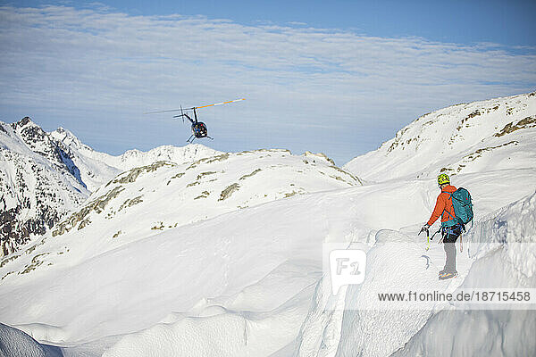 Man directing helicopter on snow-covered mountain