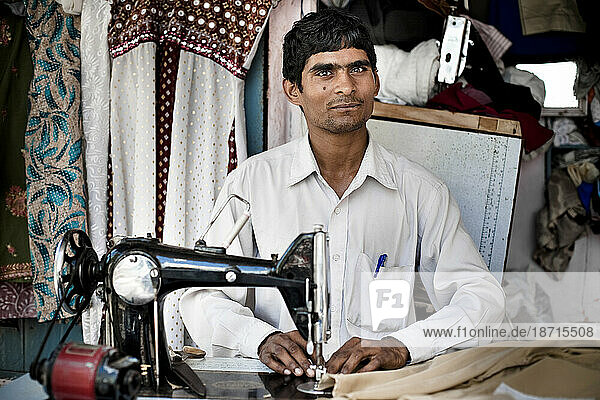 Portrait of a young man behind his sewing machine.