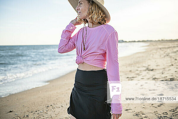 Woman in UPF sun protective clothing on beach walk