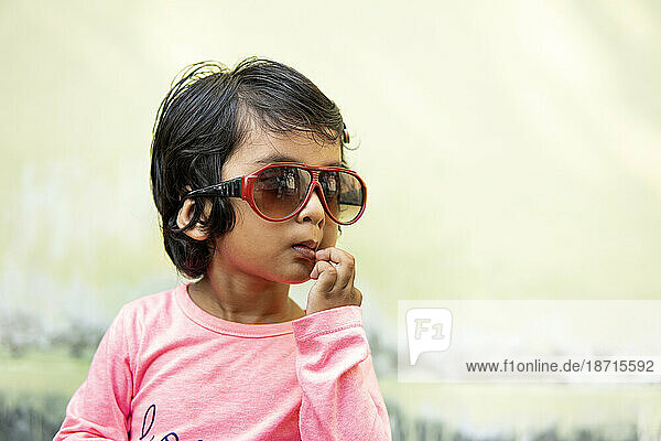 Cute little girl wearing sunglasses and making fun outdoors