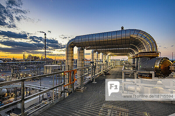Dusk is viewed through pipe in a refinery