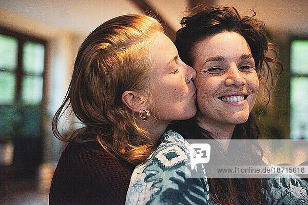 queer women couple smile and kiss happily at home in evening