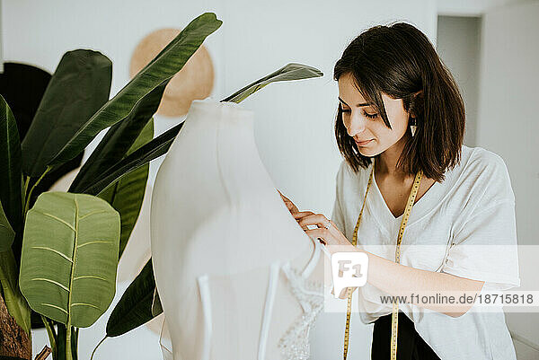 young designer with metric tape designing a wedding dress