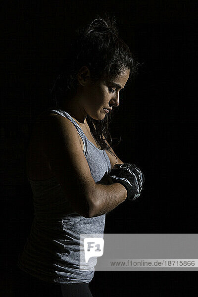 Portrait with black background of woman in gym with boxing gloves