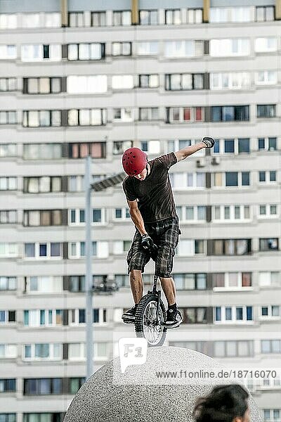 Teenage Boy Unicycling On Top Of Stone Sphere Requires Careful Balance