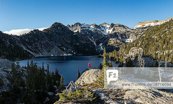 Hiker girl looks at epic mountain lake in Alpine Lakes Wilderness