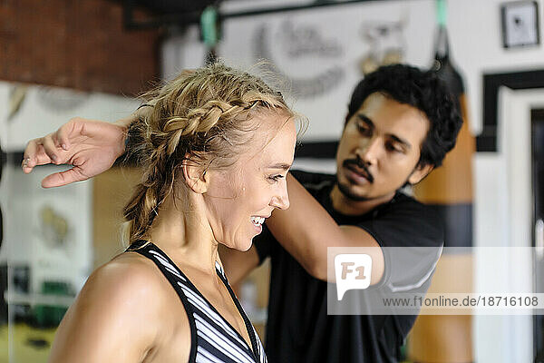 Young woman getting assistance stretching from trainer in gym  Seminyak  Bali  Indonesia