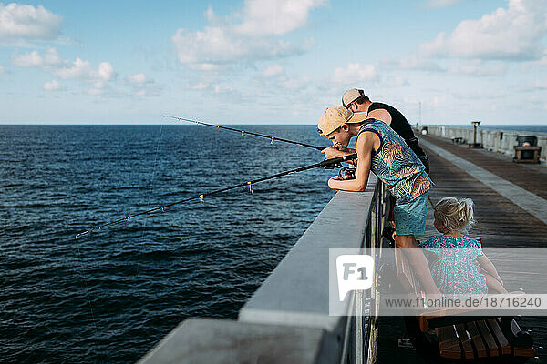 Family fishing off pier over ocean in Florida