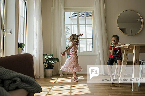 young girl dancing and playing at home with her brother