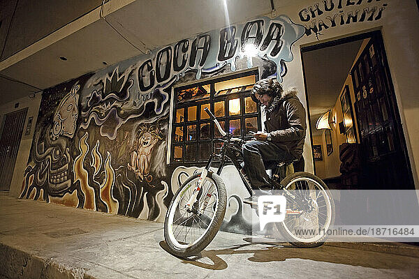 A young man on his bike with a mobile phone at the door of a bar in Huaraz  Peru.