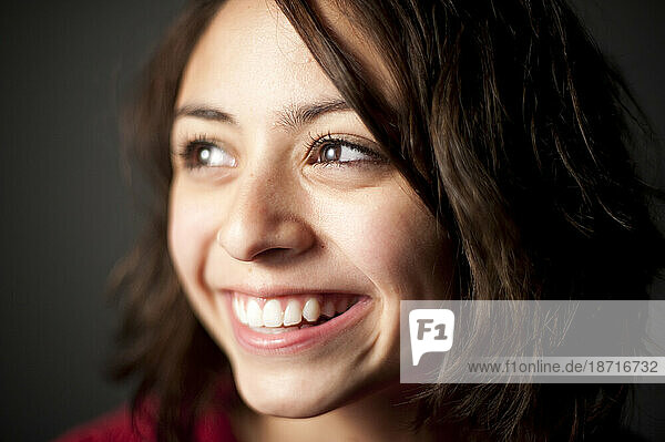 Studio portrait of 15 year old Latina girl smiling.