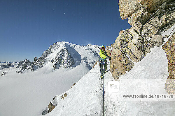 Smiling alpinist navigates steep snow traverse on the Cosmiques Ridge