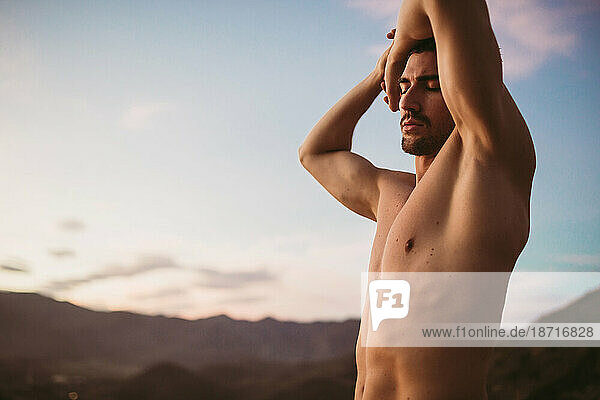 Attractive man stretching at sunset