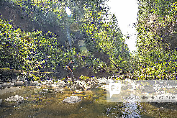 Man crossing stream in Kanaka Creek Regional Park  Maple Ridge  British Columbia  Canada