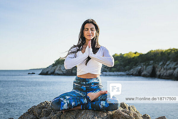 Young Woman doing Yoga on the rocks at Golden Hour