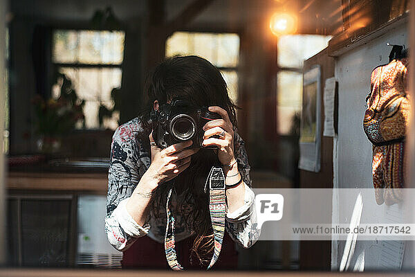 female photographer takes self portrait in mirror at home