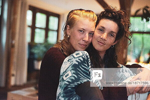 portrait of beautiful lesbian couple cuddling in wooden light home