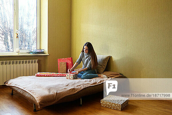 Young girl with New Year's gift wrapping at home on the bed