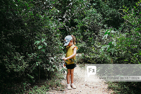 Young girl wearing rainbow hat hiking through trees