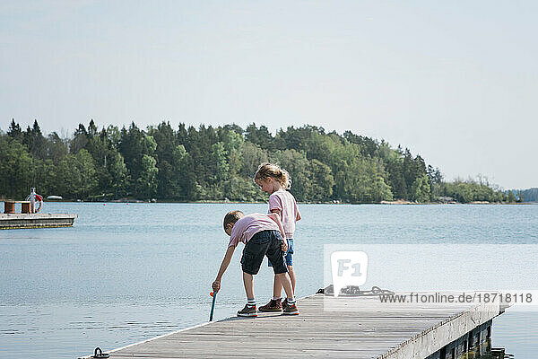 two kids fishing on a jetty by the sea