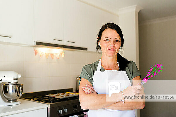A woman baker smiling in her kitchen with baking tools