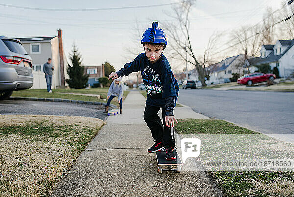 Boy on sidewalk on skateboard with helmet