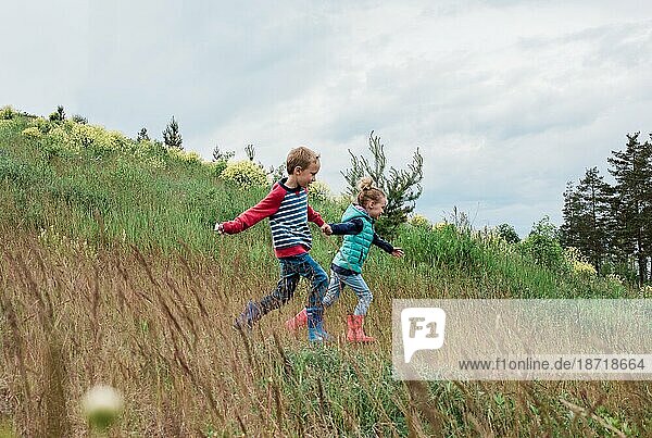 girl and boy running down a hill holding hands