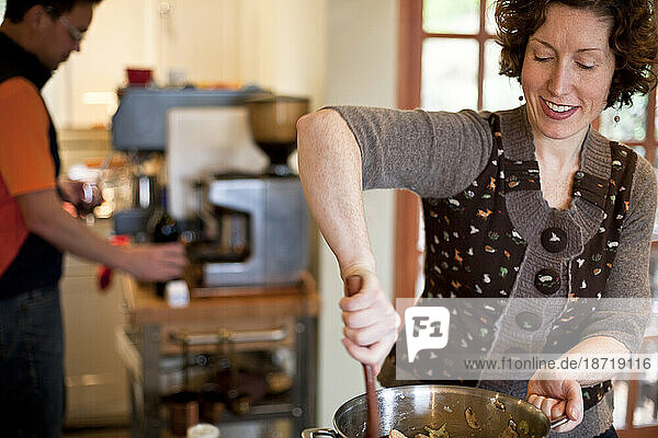 A woman smiles as she stirs a a Thanksgiving dish at the stove in a home kitchen Portland  Oregon.